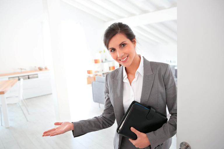Mujer con portafolio en la mano invitando a ingresar a sala de ventas